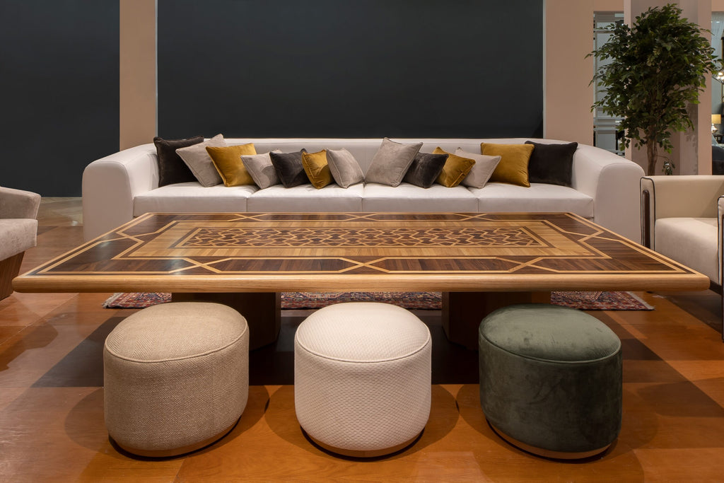 Interior of a living room featuring a white sofa, a coffee table and 3 puffs.