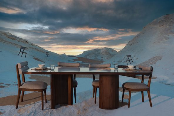 Outdoor dining area with wooden table and chairs overlooking majestic mountain landscape.